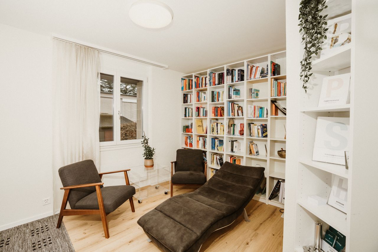 Modern reading room featuring armchairs, bookshelves, and bright natural light.